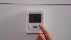 A hand adjusting the temperature on a Carrier thermostat